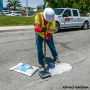 A worker compacting the HP Concrete Cold Patch on a roadway using a hand tamper.'