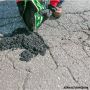Close-up of a contractor pouring HP Asphalt Cold Patch into a pavement crack for repair.'