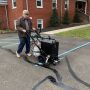 Contractor operating the RY10 Crack Filling Machine, applying Deery 102 Hot Applied Oil Jacketed Sealant to pavement cracks.'