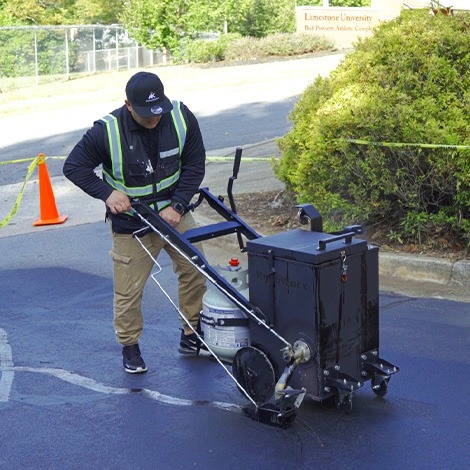 Worker using hot crack filler machine on asphalt cracks